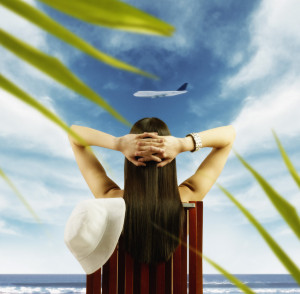 Young woman watching airplane fly by from tropical beach --- Image by © Royalty-Free/Corbis